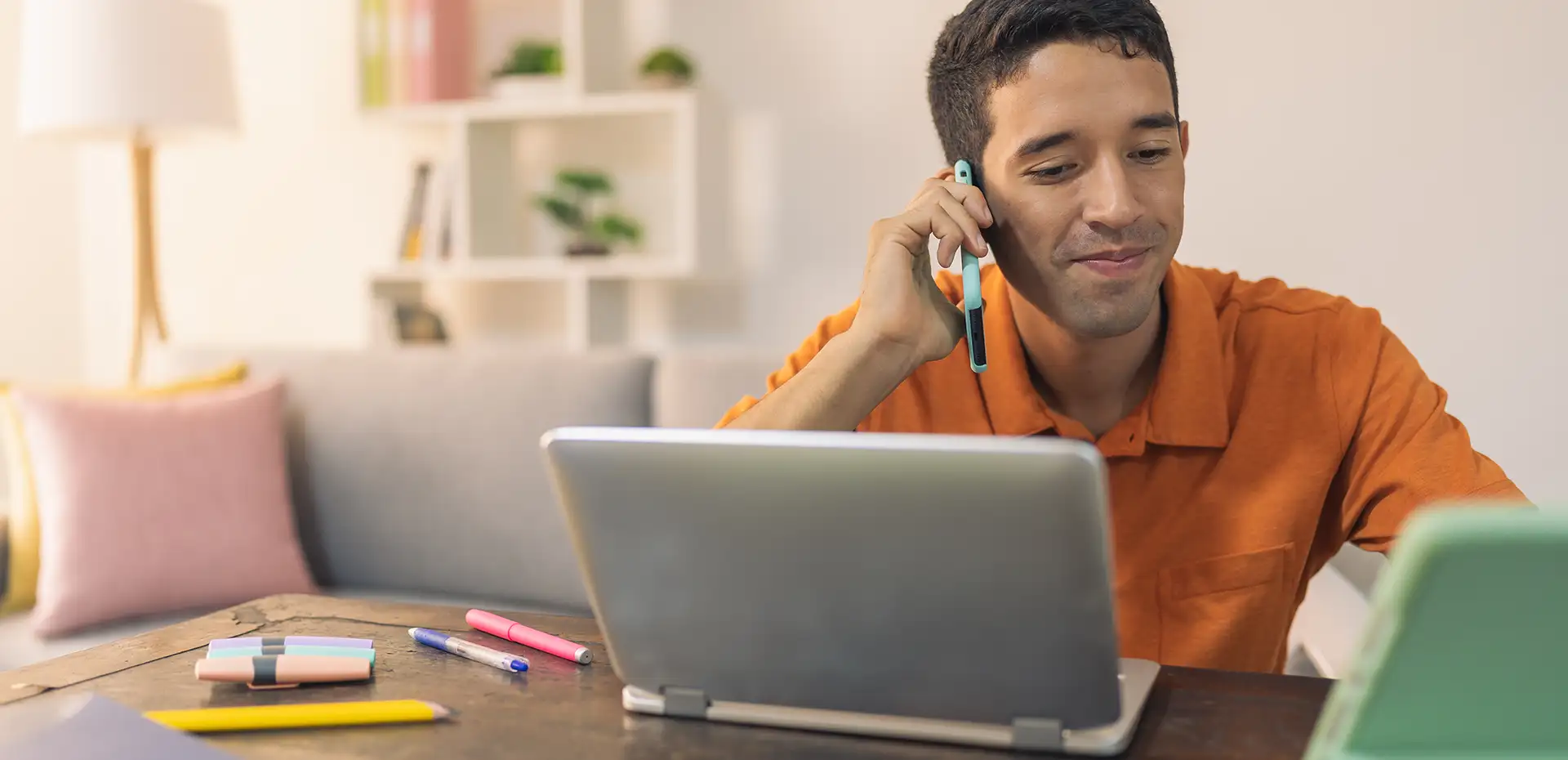 Persona hablando por celular con laptop enfrente