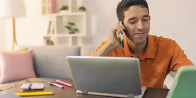 Persona hablando por teléfono y laptop al frente