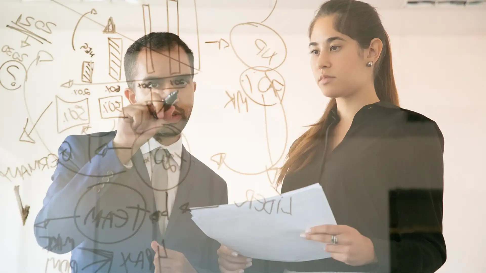 Dos personas escribiendo en pared de vidrio