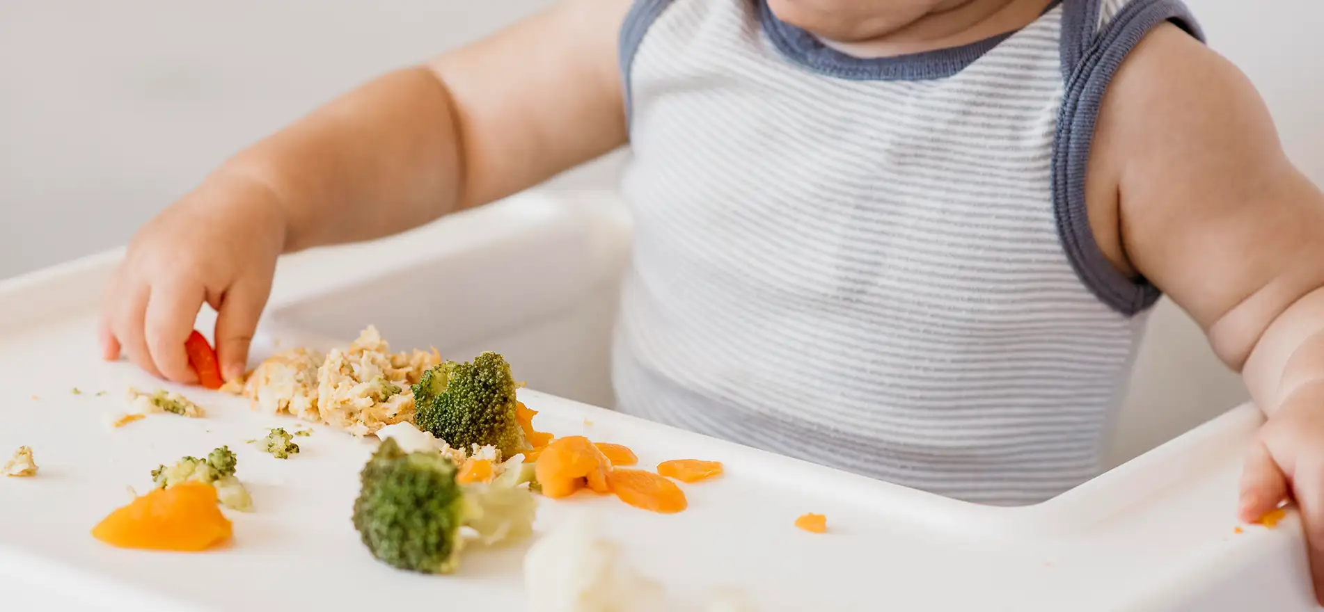 Bebé tomando verduras con las manos