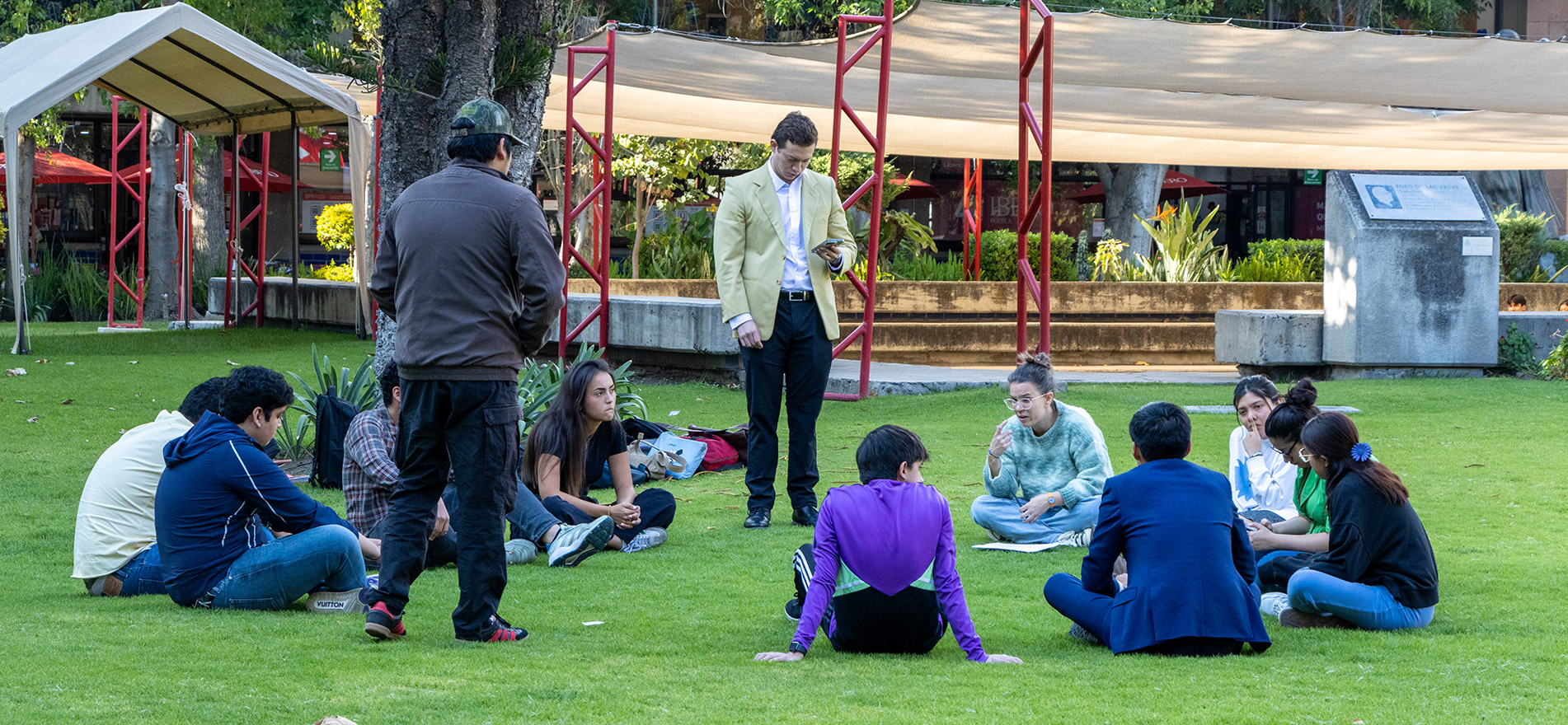 alumnos reunidos sentados en el pasto