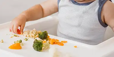 Bebe tomando verduras con la mano