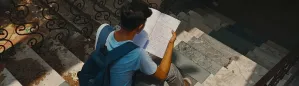 Alumno leyendo en unas escaleras